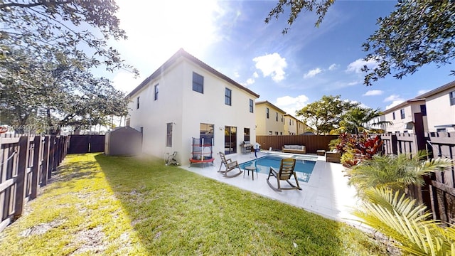 rear view of property featuring a lawn, an outdoor hangout area, a patio area, and a fenced in pool