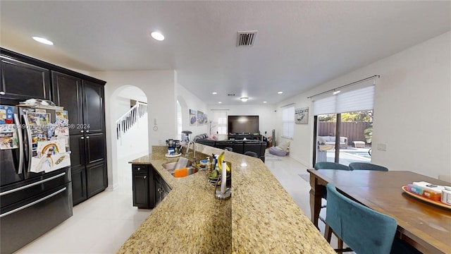 kitchen featuring light stone counters, sink, and stainless steel refrigerator