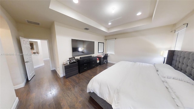 bedroom with a raised ceiling and dark wood-type flooring