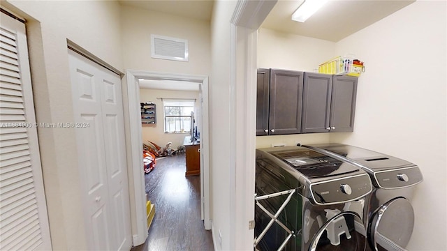 laundry room with washing machine and dryer, dark hardwood / wood-style flooring, and cabinets