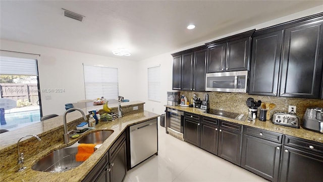 kitchen with decorative backsplash, sink, light stone counters, and appliances with stainless steel finishes