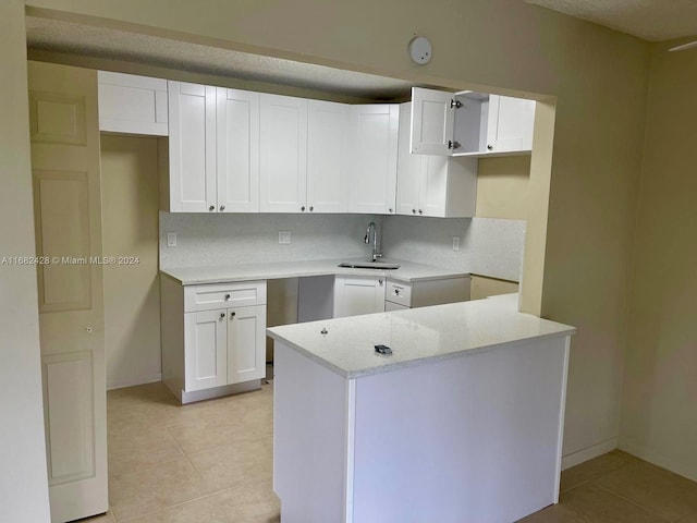 kitchen featuring sink, white cabinets, light stone counters, and light tile patterned floors