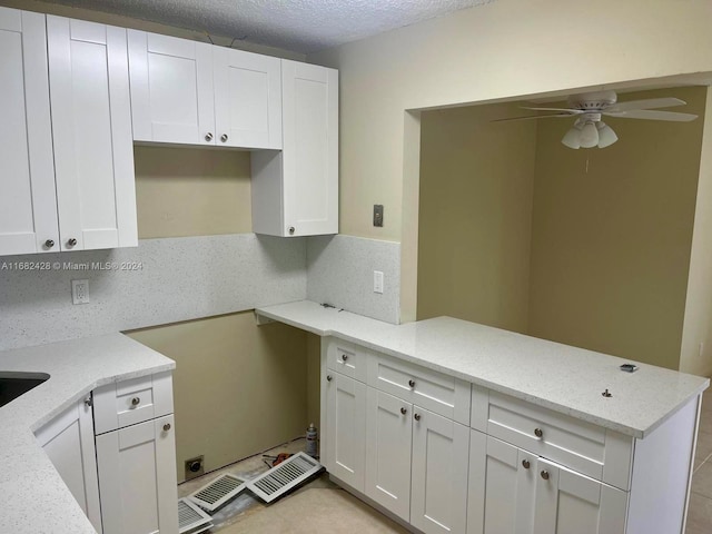 kitchen featuring kitchen peninsula, white cabinets, light stone countertops, and a textured ceiling