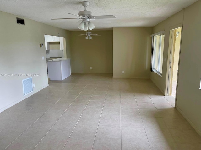 empty room with a textured ceiling, light tile patterned floors, and ceiling fan