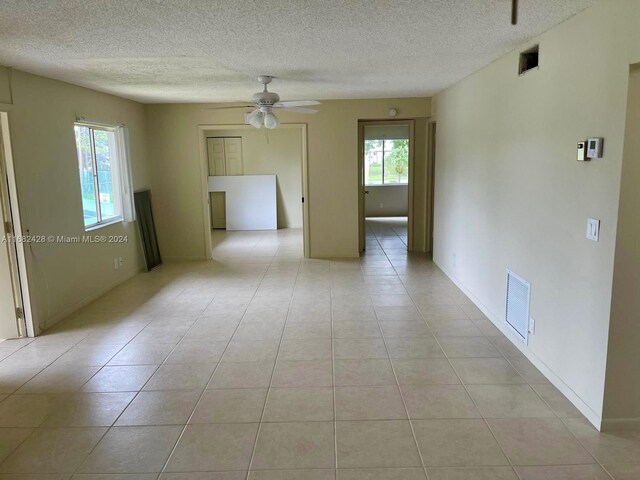 spare room featuring light tile patterned flooring, ceiling fan, and plenty of natural light