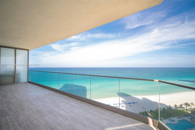 balcony with a water view and a view of the beach