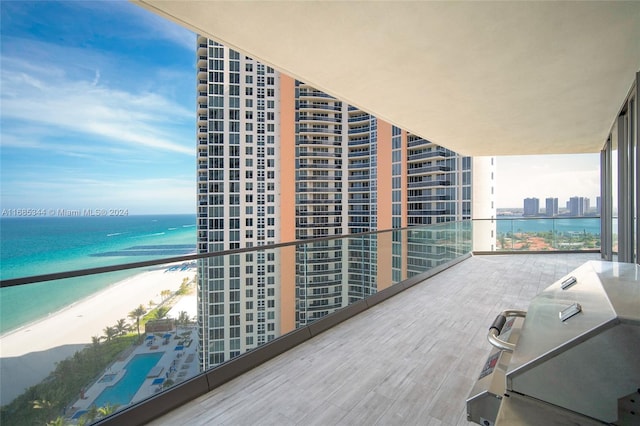 balcony with a water view, a view of the beach, and a grill