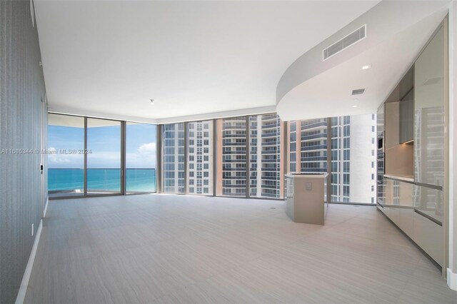 unfurnished living room featuring expansive windows and a water view