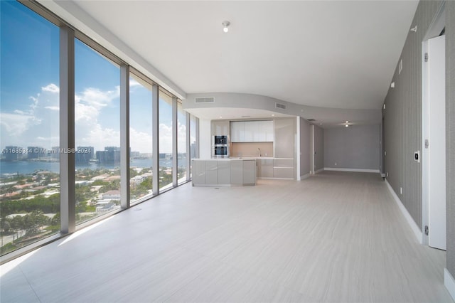 unfurnished living room featuring a wealth of natural light, a wall of windows, and a water view