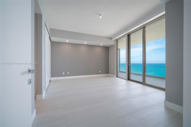 unfurnished room featuring a wall of windows and a water view