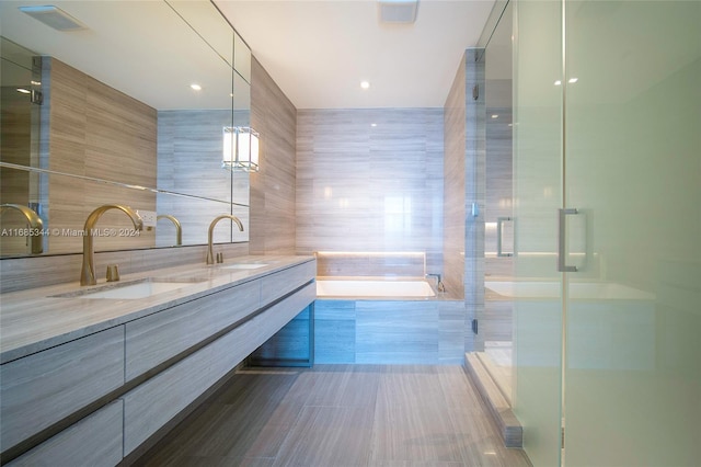 bathroom featuring tile walls, vanity, and plus walk in shower