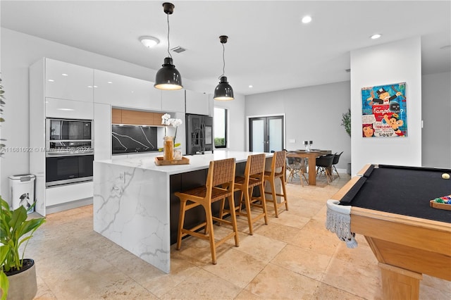 kitchen with pool table, white cabinets, a kitchen island, black appliances, and decorative light fixtures