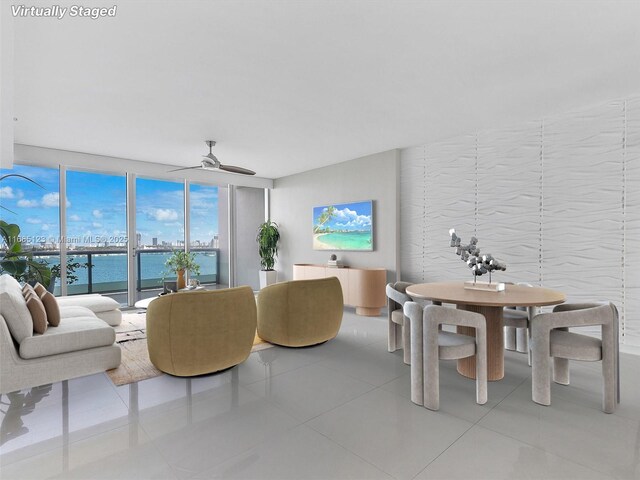 tiled living room featuring a wall of windows, a water view, and ceiling fan