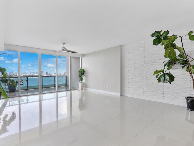 spare room featuring a water view, a wall of windows, ceiling fan, and light tile patterned flooring