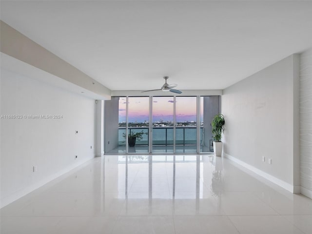 tiled empty room featuring ceiling fan and floor to ceiling windows