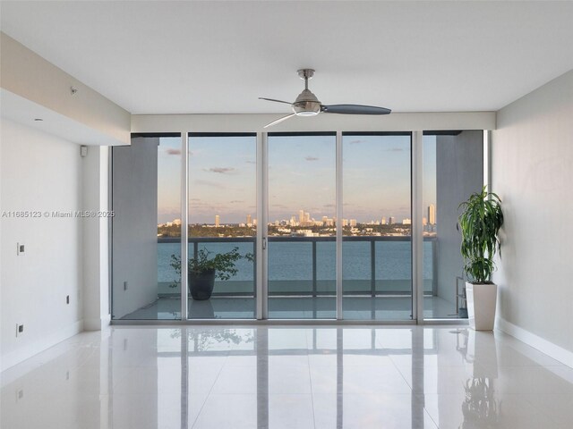 spare room with floor to ceiling windows, a water view, and ceiling fan