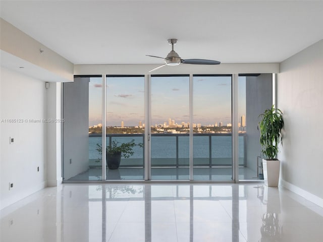unfurnished room featuring a wealth of natural light, ceiling fan, and a water view