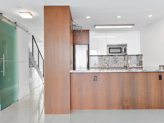 kitchen with sink, tasteful backsplash, appliances with stainless steel finishes, light stone countertops, and white cabinets