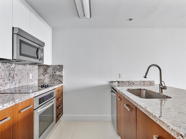 kitchen with sink, light tile patterned floors, backsplash, stainless steel appliances, and white cabinets