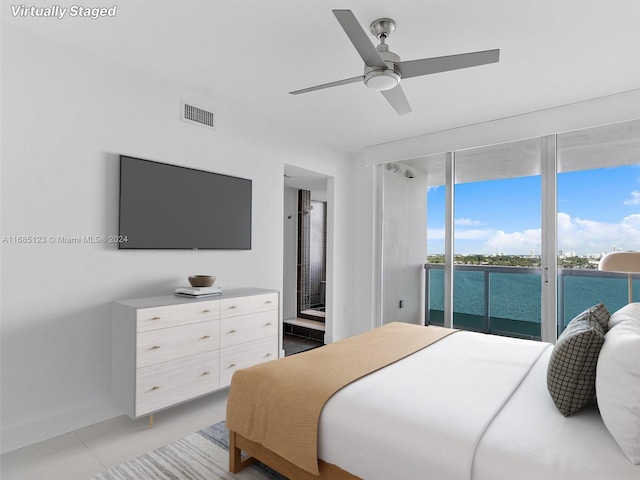 bedroom featuring ceiling fan, light tile patterned floors, ensuite bath, and access to exterior