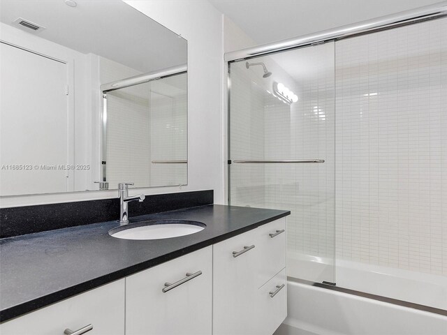 bathroom featuring vanity and shower / bath combination with glass door