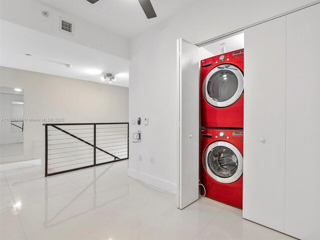 laundry area with ceiling fan, stacked washer / drying machine, and light tile patterned floors