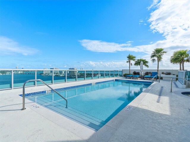 view of pool featuring a patio area and a water view