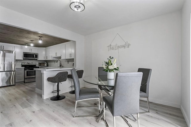 dining space with light hardwood / wood-style flooring and sink