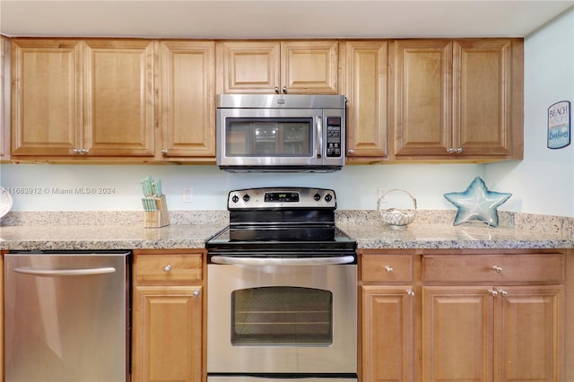 kitchen with appliances with stainless steel finishes and light stone countertops