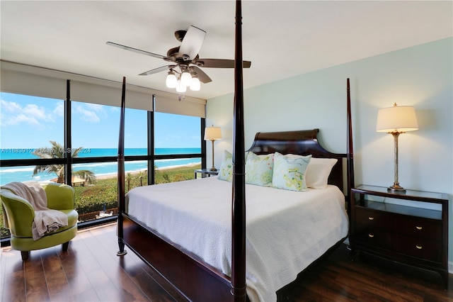 bedroom featuring a beach view, ceiling fan, a water view, and dark hardwood / wood-style flooring