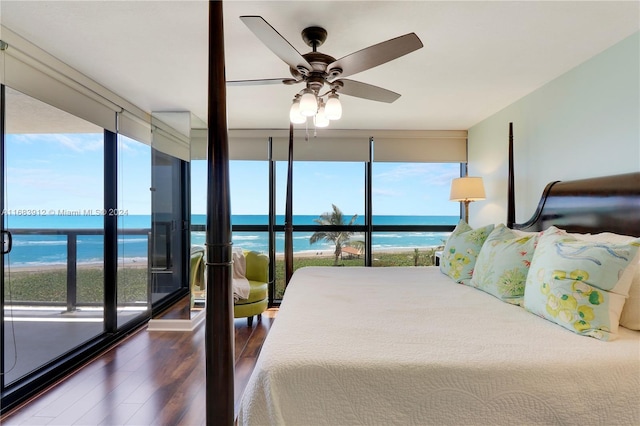 bedroom featuring multiple windows, ceiling fan, a water view, and dark hardwood / wood-style flooring