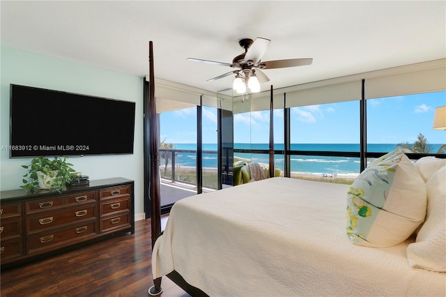 bedroom featuring ceiling fan, access to exterior, dark wood-type flooring, a view of the beach, and a water view