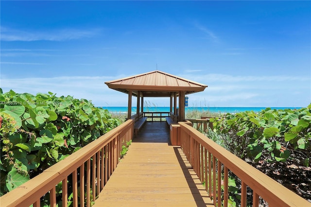 surrounding community with a gazebo, a water view, and a view of the beach