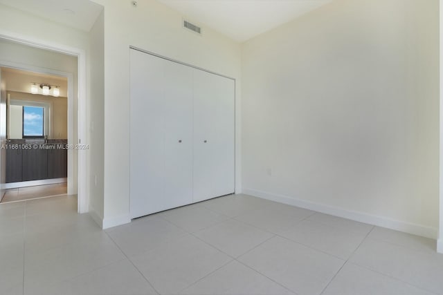 unfurnished bedroom with light tile patterned flooring and a closet