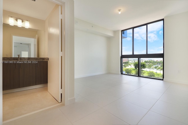 empty room with sink, floor to ceiling windows, and light tile patterned floors