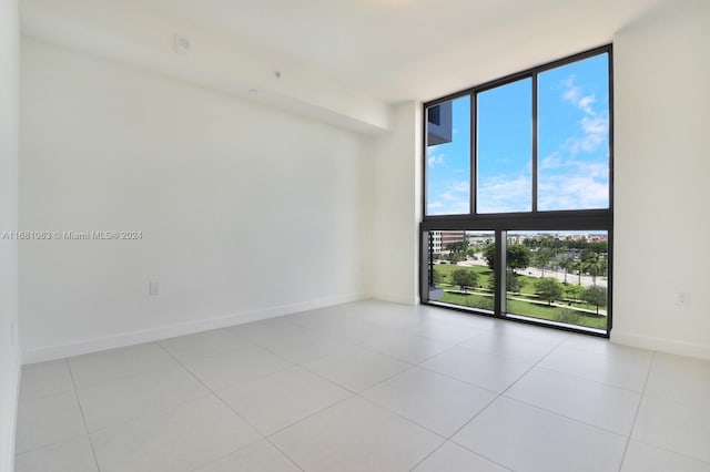 unfurnished room with a wall of windows and light tile patterned floors