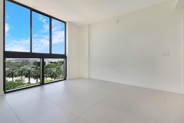 empty room featuring a wall of windows, light tile patterned flooring, and plenty of natural light