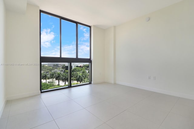 empty room with a wealth of natural light, a wall of windows, and light tile patterned flooring