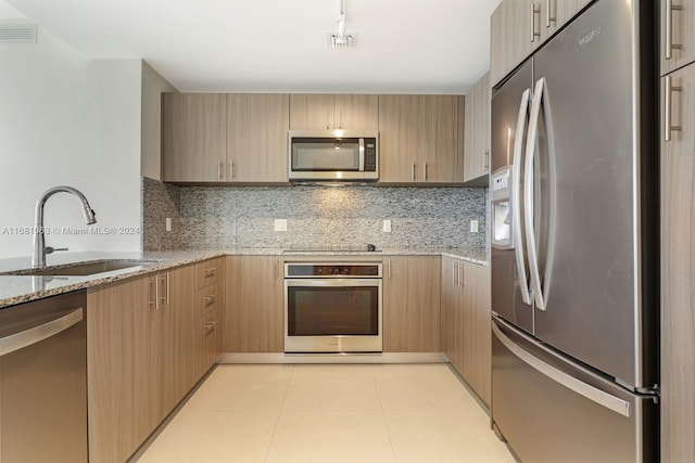 kitchen featuring stainless steel appliances, sink, light brown cabinetry, and backsplash