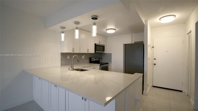 kitchen with stainless steel appliances, light countertops, white cabinetry, a sink, and a peninsula