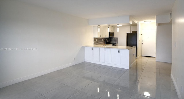 kitchen with tasteful backsplash, light countertops, white cabinets, a sink, and a peninsula