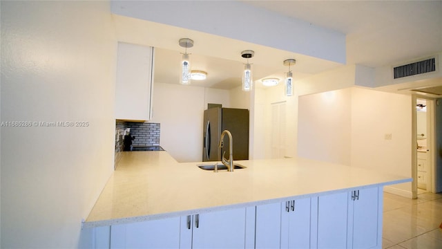 kitchen featuring visible vents, white cabinets, freestanding refrigerator, light countertops, and a sink