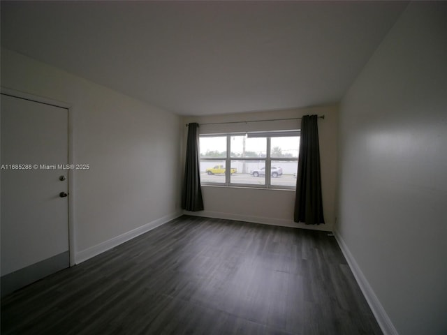 spare room featuring dark wood-style floors and baseboards