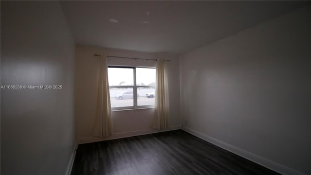 spare room with dark wood-style flooring and baseboards