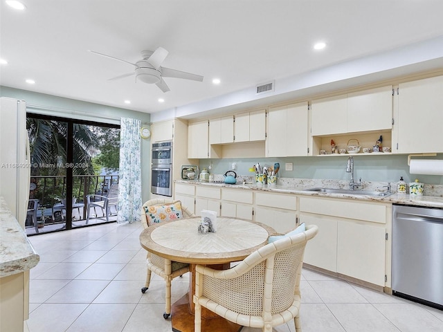 kitchen featuring stainless steel appliances, light stone countertops, light tile patterned floors, and sink