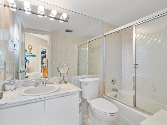 full bathroom with toilet, vanity, and shower / bath combination with glass door