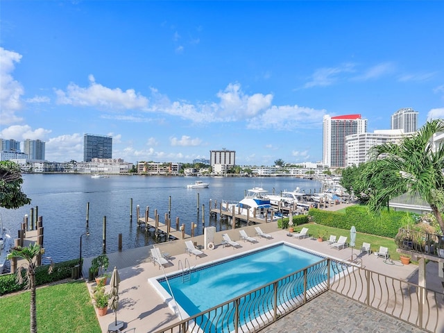 view of swimming pool featuring a dock, a lawn, a patio, and a water view