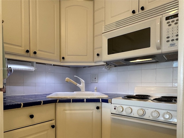 kitchen featuring backsplash, sink, tile counters, and white appliances