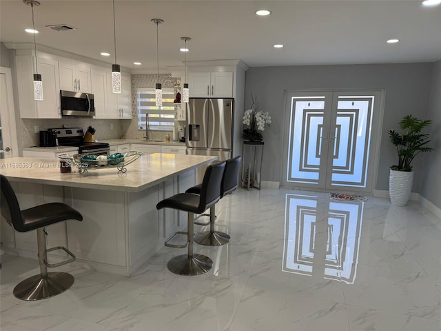 kitchen featuring hanging light fixtures, appliances with stainless steel finishes, a center island, and white cabinets