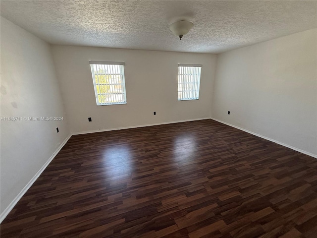 unfurnished room featuring dark hardwood / wood-style floors, a textured ceiling, and a wealth of natural light